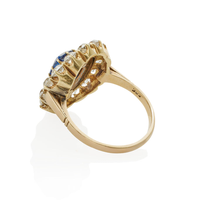 Macklowe Gallery An English Antique 15 karat gold/silver top ring with sapphire and diamonds. The ring centers on a no heat oval-cut sapphire with an approximate weight of .95 carat, 14 old mine-cut diamonds with an approximate total weight of 1.40 carats, and 19 rose-cut diamonds with an approximate total weight of .19 carat.  Designed in a classic oval cluster motif.  